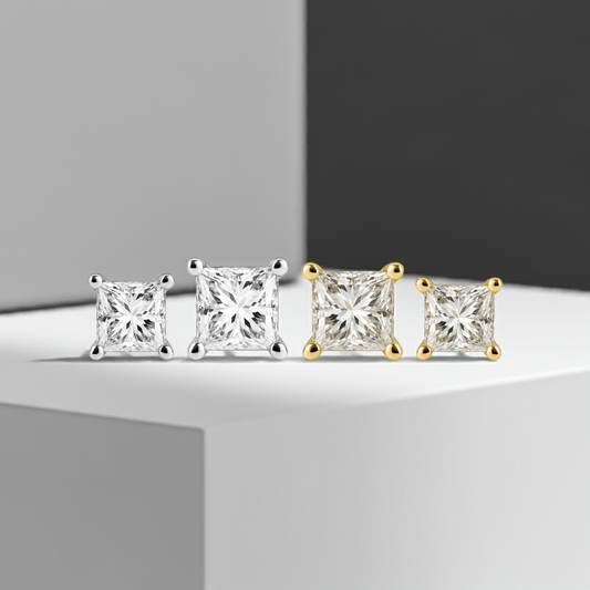 Pair of diamond stud earrings, one in white gold and one in yellow gold, on a white background.